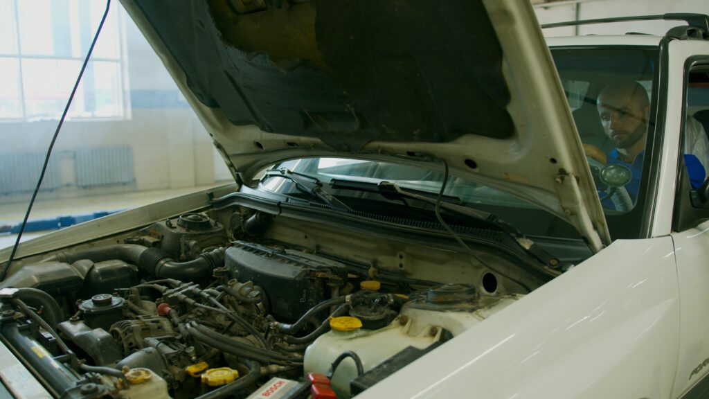 Mechanic inspecting a car engine under an open hood